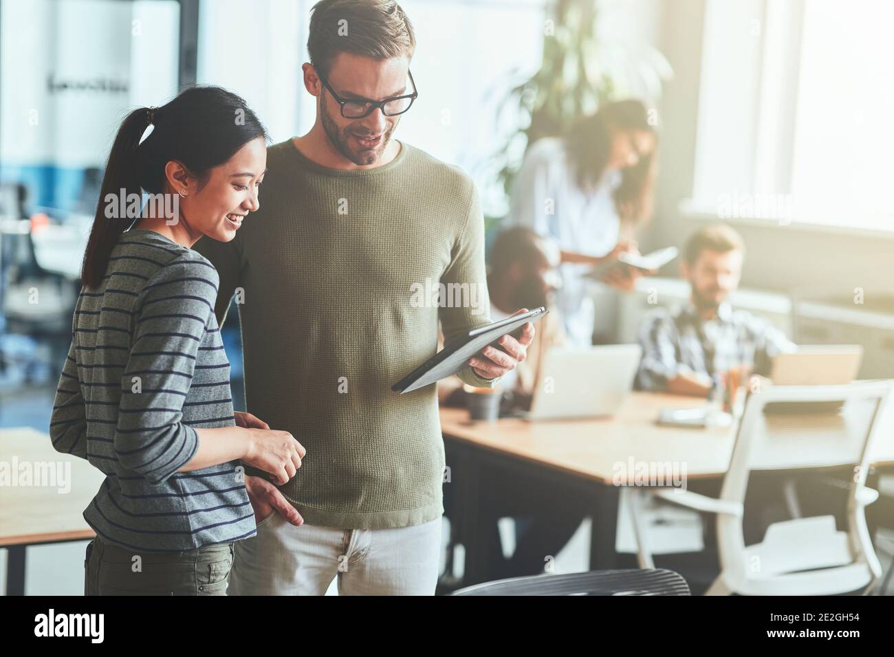 Two ambitious young people using tablet in coworking space Stock Photo