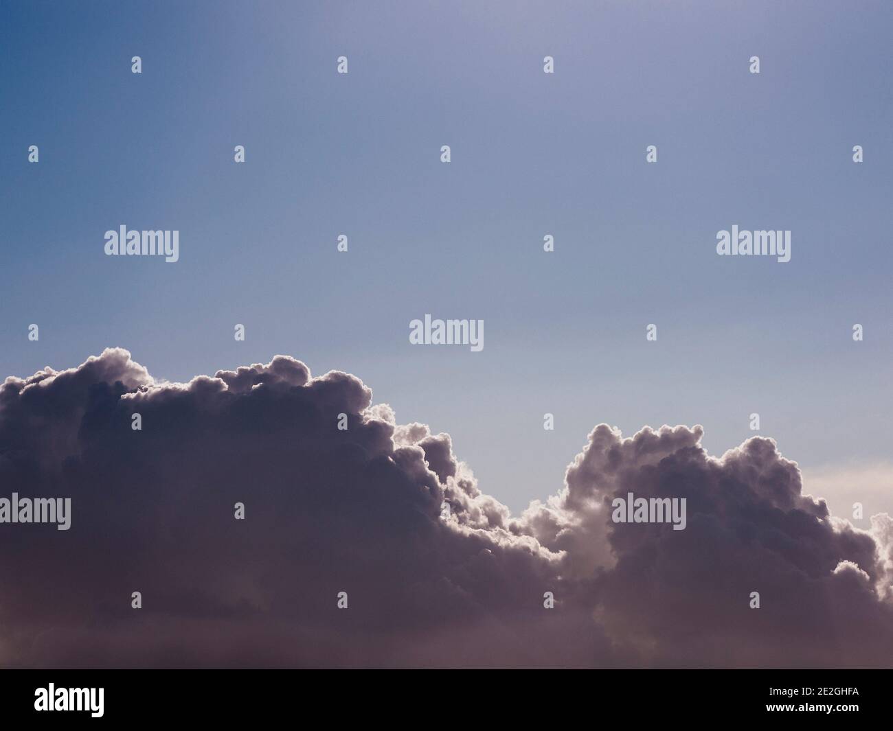 Fluffy cumulus clouds in sunny blue sky Stock Photo