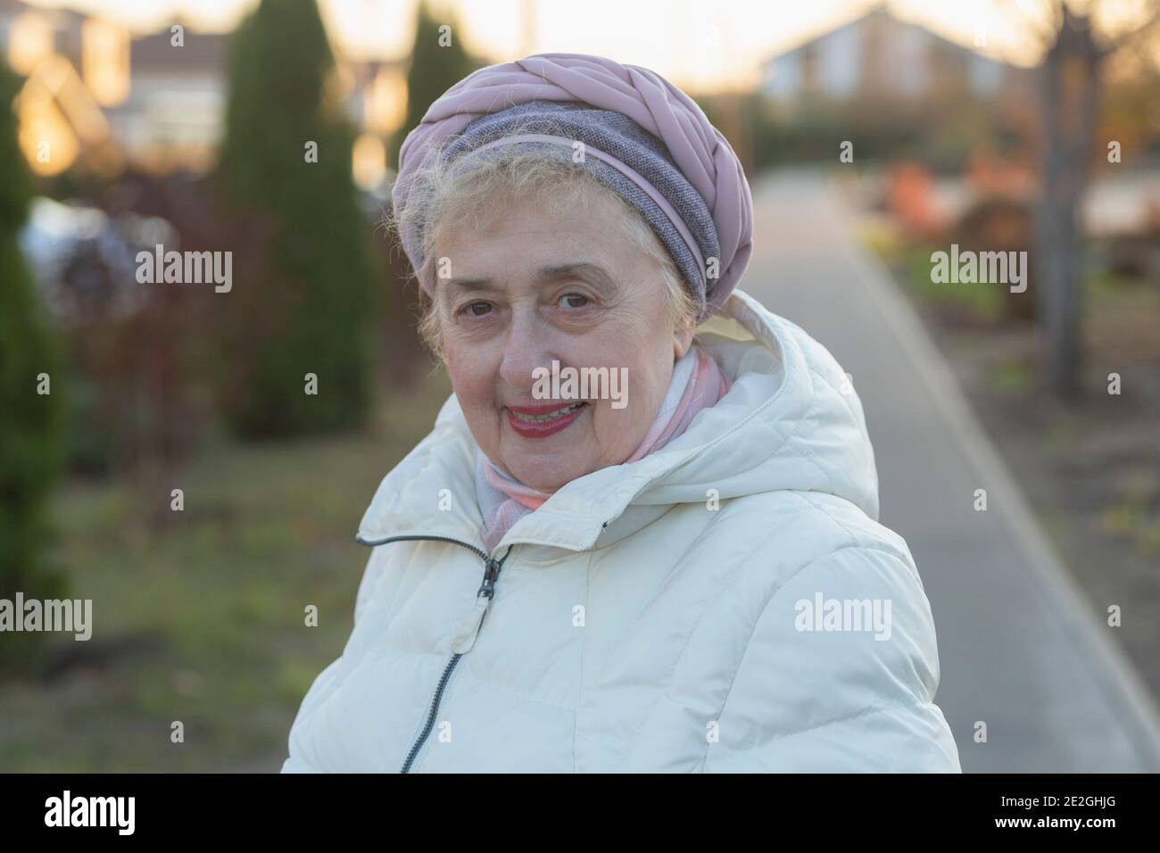 Portrait happy beautiful senior woman in winter coat on sidewalk Stock Photo