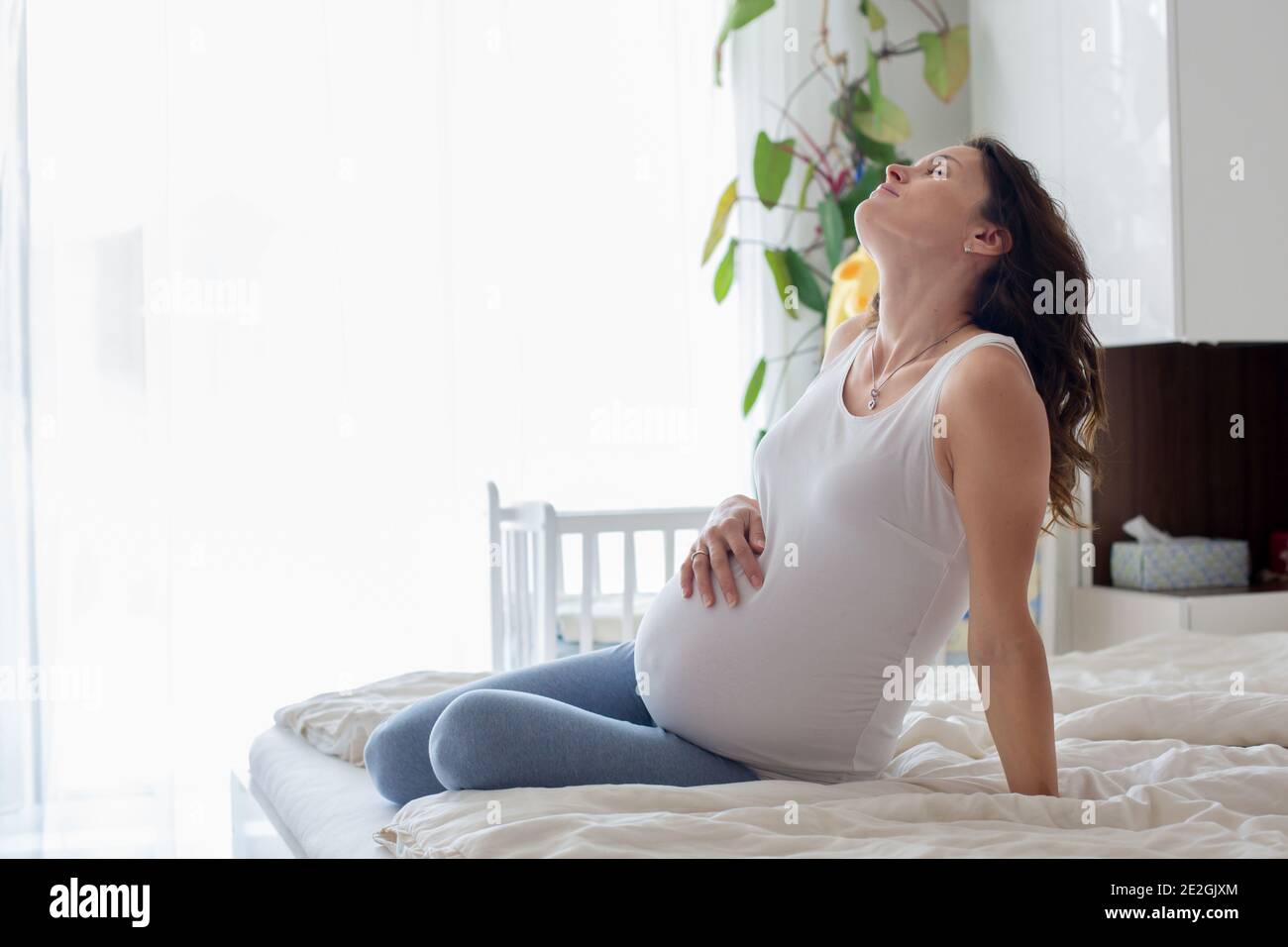Young beautiful pregnant woman, in pain with labor contraction, sitting