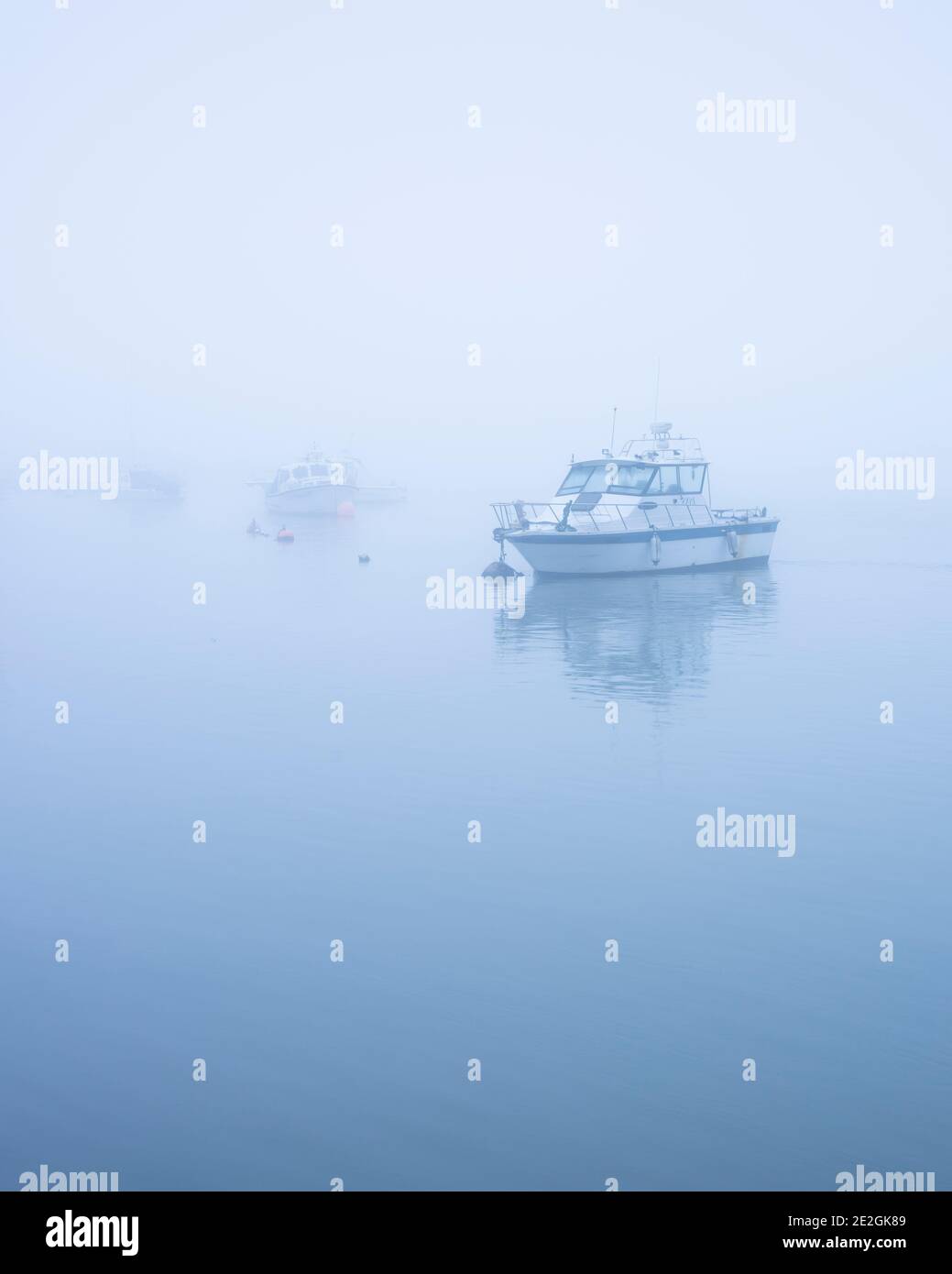 Boats moored at the Swale estuary in North Kent on a foggy morning. Stock Photo