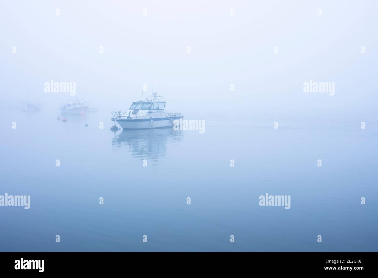Boats moored at the Swale estuary in North Kent on a foggy morning. Stock Photo