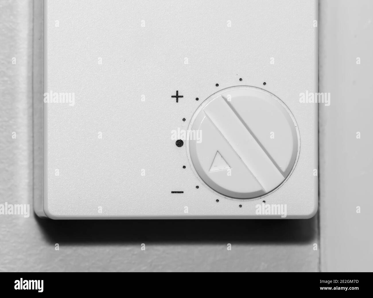 Simple wall mounted white thermostat dial for adjusting room temperature. Stock Photo
