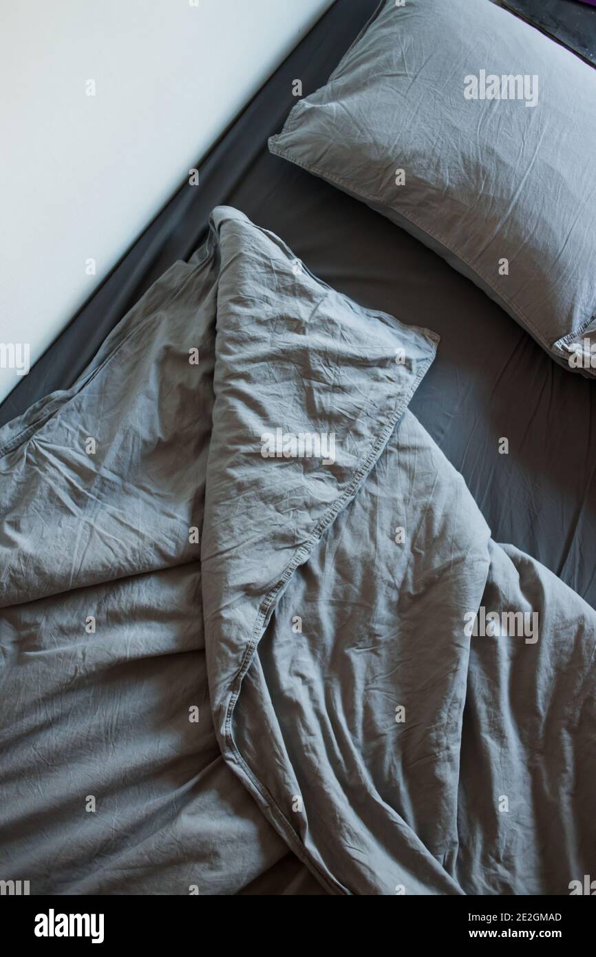 The view from the top of the morning grey bed after sleep. Blankets, sheets  and pillows Stock Photo - Alamy