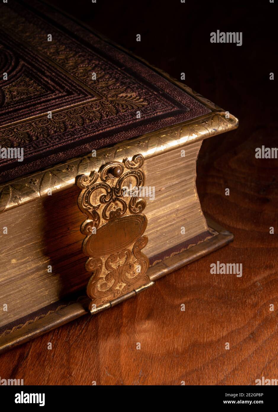 A leather bound antique book with a decorative metal clasp photographed on a glossy wooden surface Stock Photo