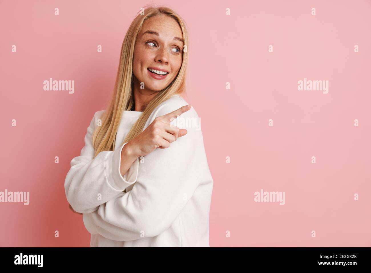 Happy beautiful girl smiling and pointing finger aside isolated over ...