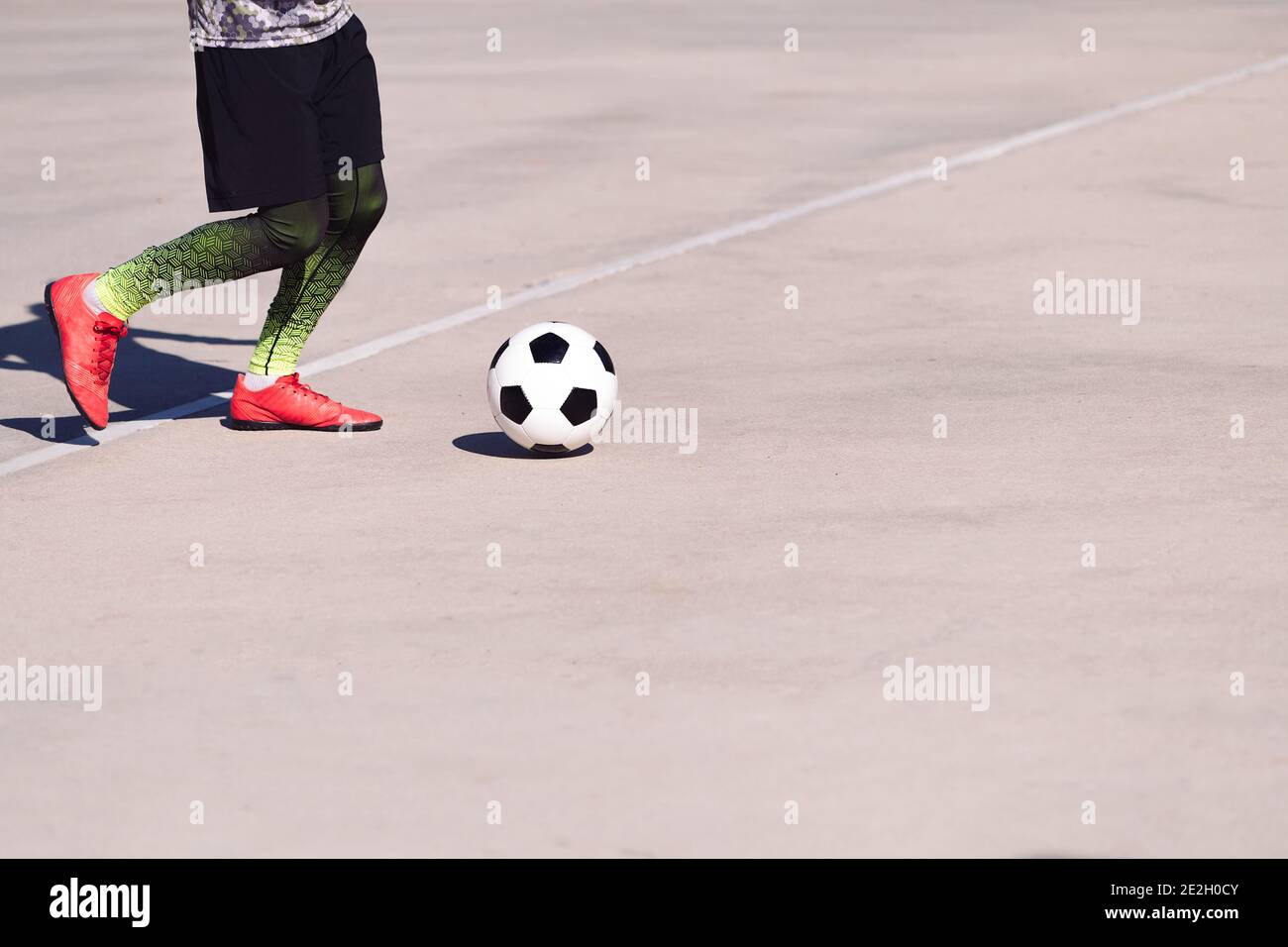 legs of an unrecognizable football player playing with the ball in a concrete soccer court, concept of healthy lifestyle and urban sport in the city, Stock Photo