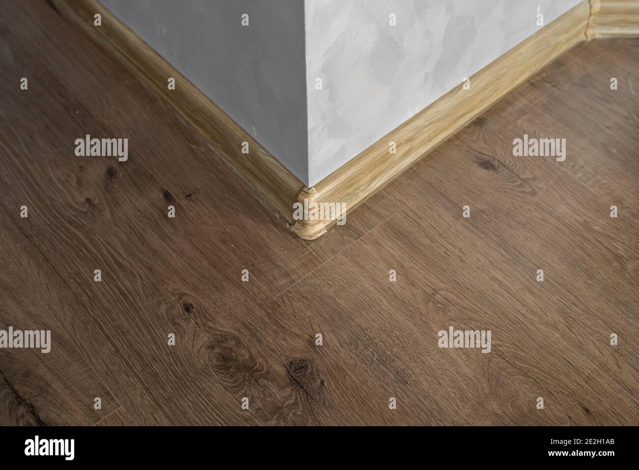 Laminate with plastic baseboard with a wooden texture. Newly installed wooden laminate flooring