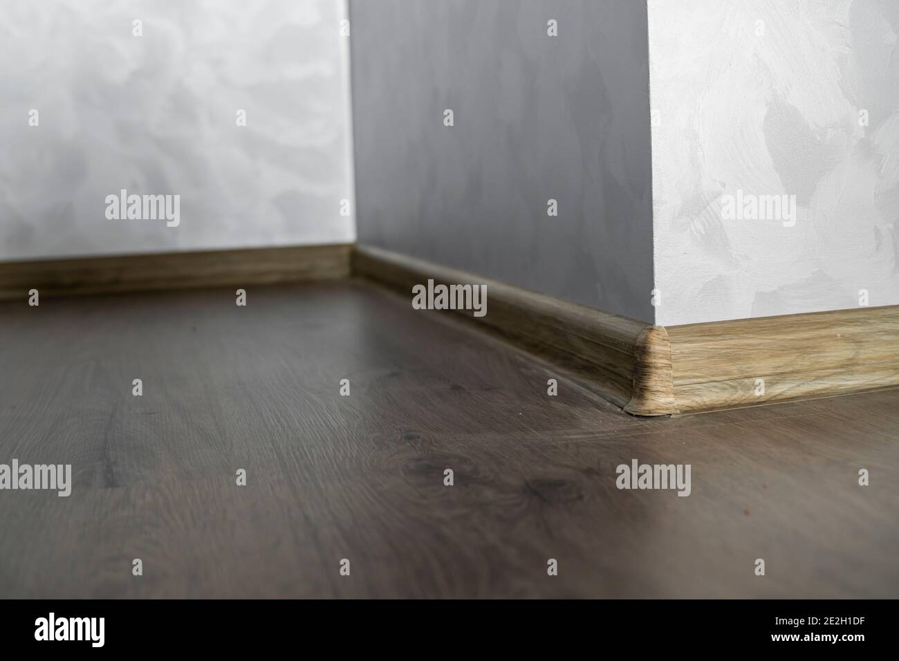 Laminate with plastic baseboard with a wooden texture. Newly installed wooden laminate flooring