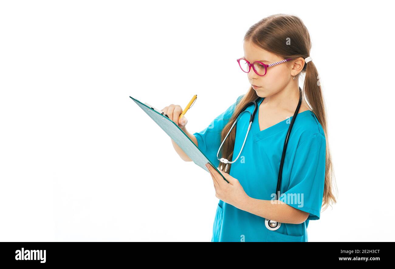 Cute little girl writes medical treatment on her clipboard. Child plays doctor, future profession. White background Stock Photo
