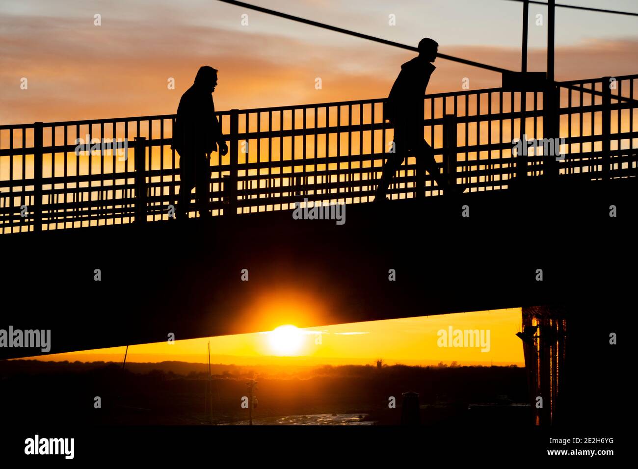 Two people walking silhouetted with bright sunset behind them Stock ...