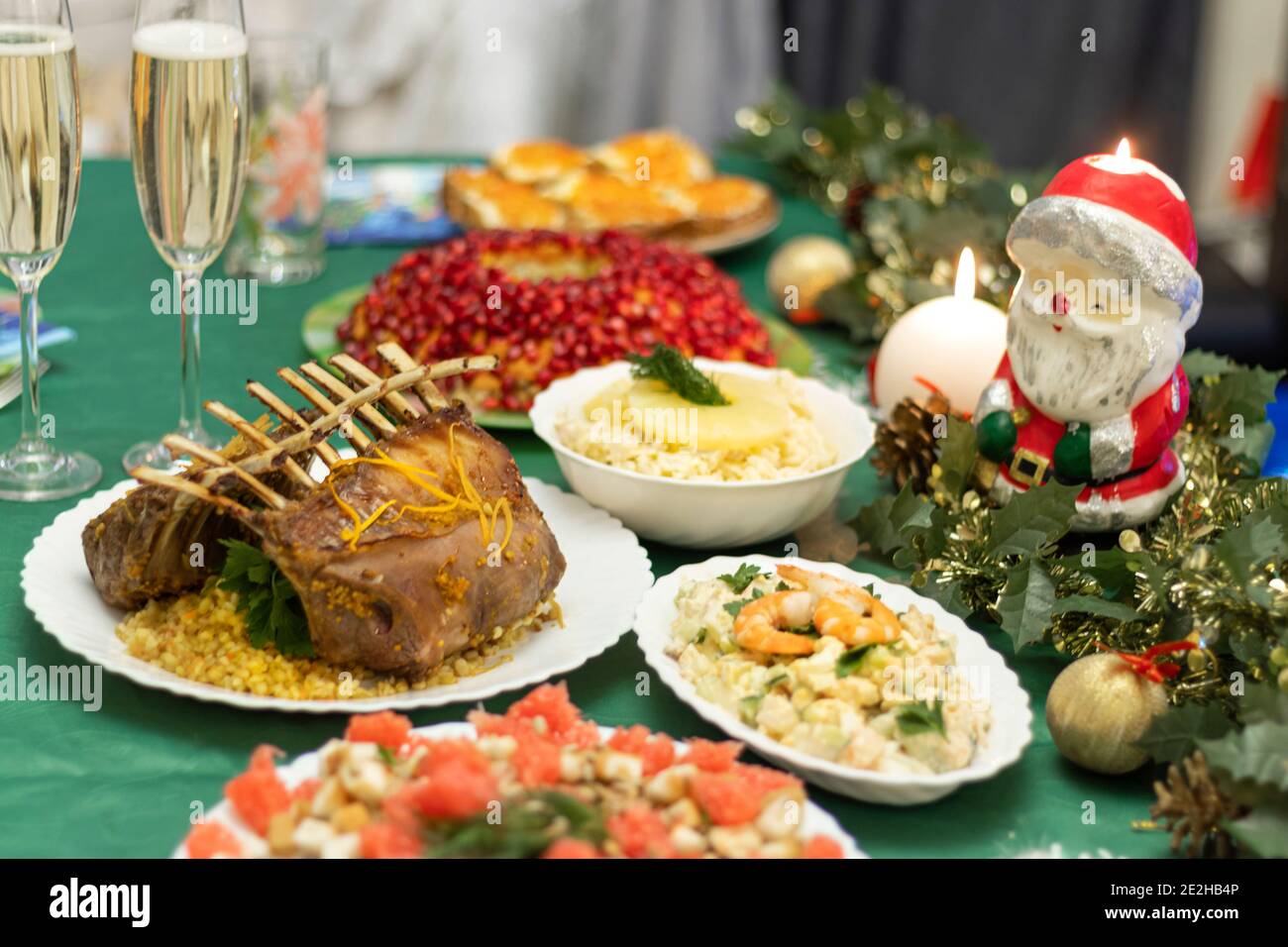 A festive table with many delicious dishes. Lamb rack, two glasses of champagne, salads and snacks on the festive table. Celebrations at home. Stock Photo