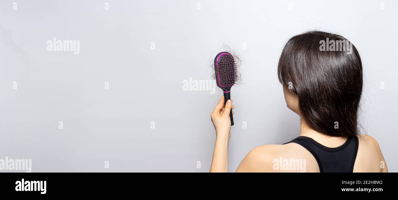 The girl is holding a hairbrush with lost hair. Hair loss, care and treatment. Trichologist, trichology. Banner with place for text copy space. Stock Photo