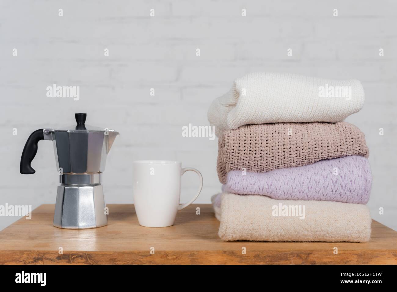 Coffee maker, cup and woolen sweaters on wooden table Stock Photo - Alamy