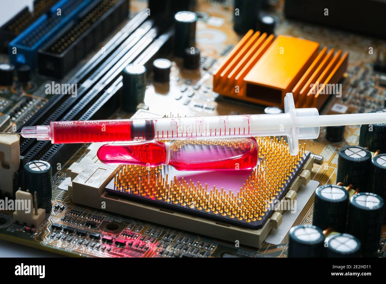 glass ampoule with red medicine with syringe on socket with cpu chip with contact legs on motherboard with microelectronic components, theme of cybern Stock Photo