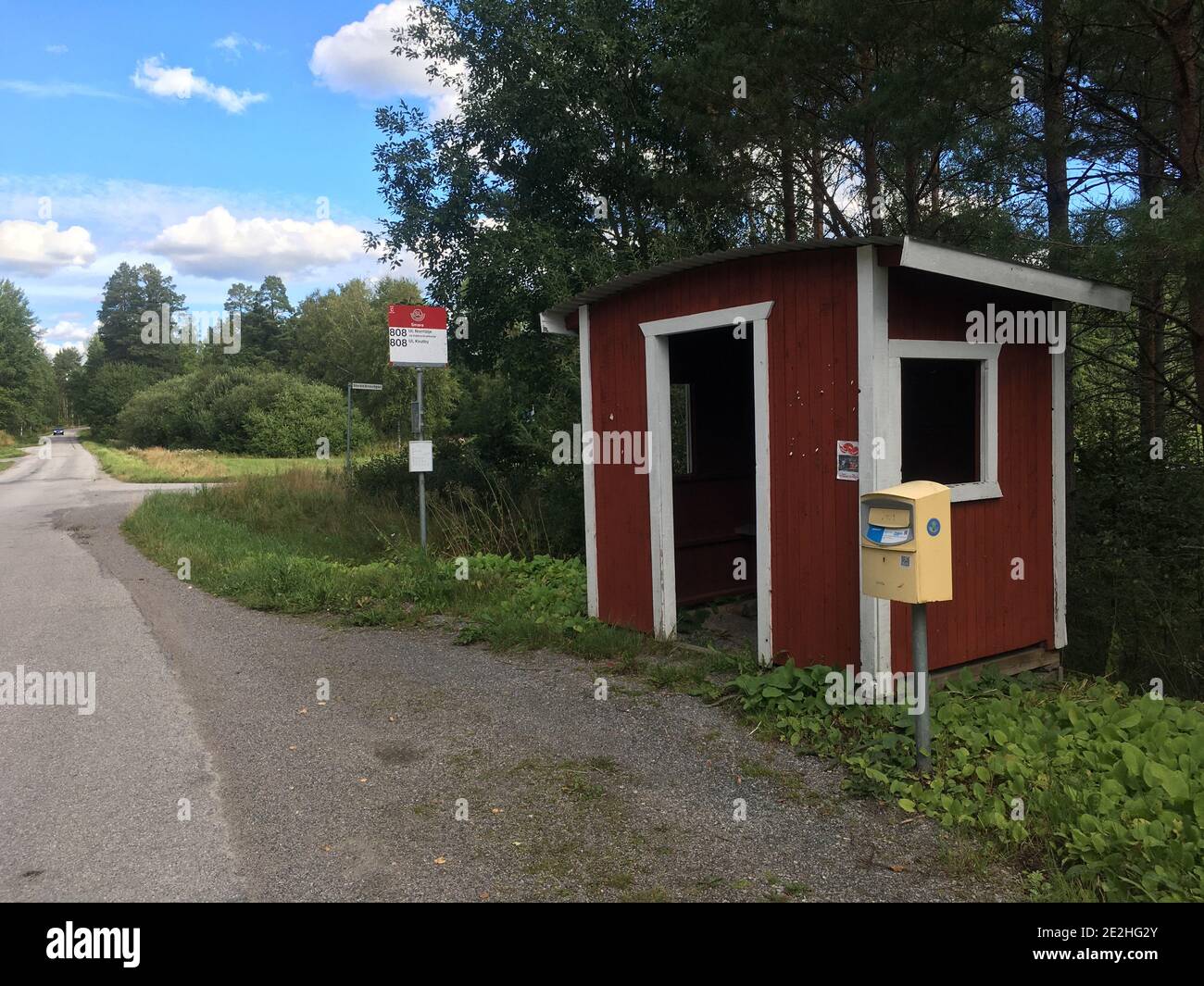 Stockholm, Sweden - August 26, 2020: A bus stop in the depopulated countryside of Sweden. With a post box beside it and a small red house to take cove Stock Photo