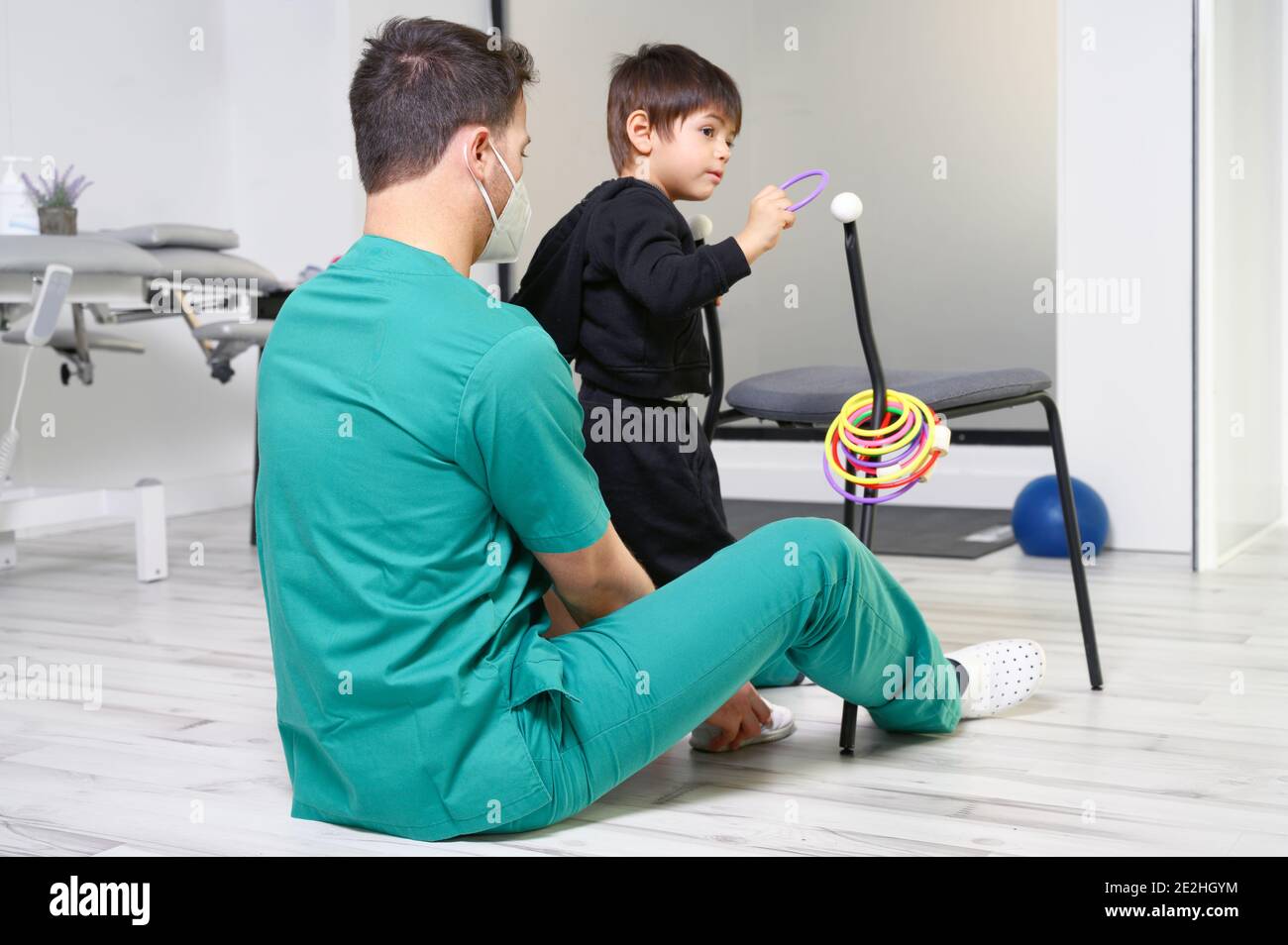 Child with cerebral palsy on physiotherapy in a children therapy center. Boy with disability doing exercises with physiotherapists in rehabitation centre. High quality photo. Stock Photo