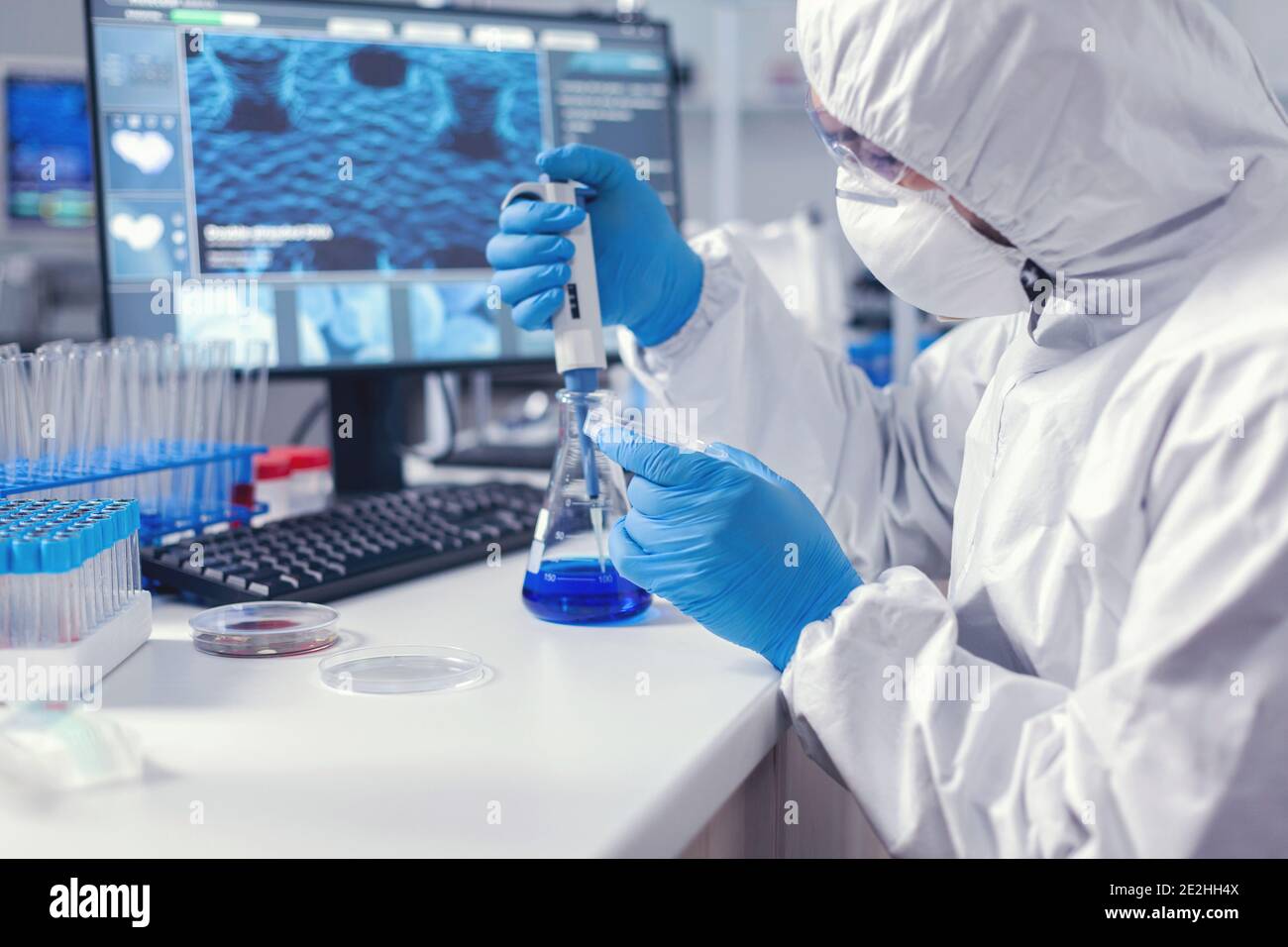 Man in microbiology lab holding petri dish working with micropipette