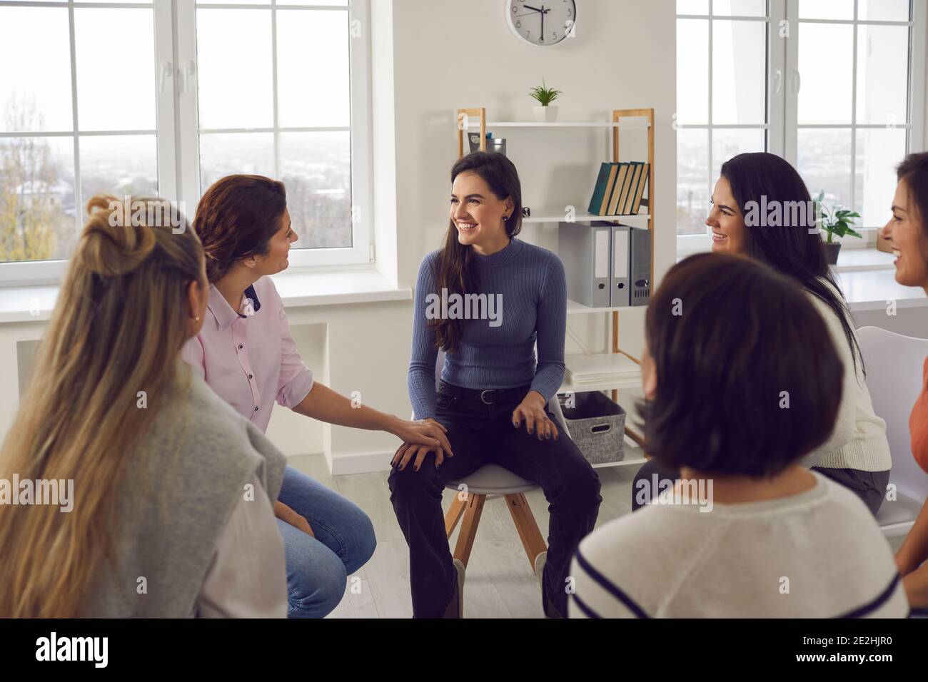 Happy women sitting in circle, smiling, talking and sharing positivity in group meeting Stock Photo