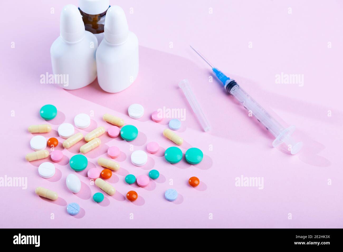 Set of many medical medicines, syringe, spray, bottles of nose drops, scattered  colorful tablets, capsules on pink background, vitamins, horizontal, Stock Photo