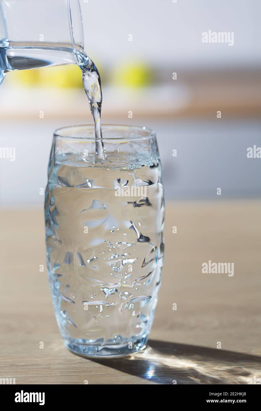 https://c8.alamy.com/comp/2E2HKJ8/glass-of-water-is-poured-from-the-jug-into-a-single-glass-in-a-kitchen-table-vertical-orientation-2E2HKJ8.jpg