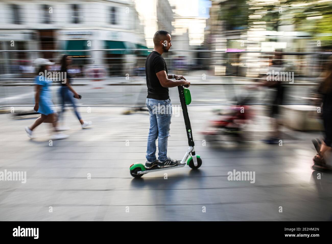 Man riding an electric scooter on a pavement, without a helmet, in Lyon (centraleastern France