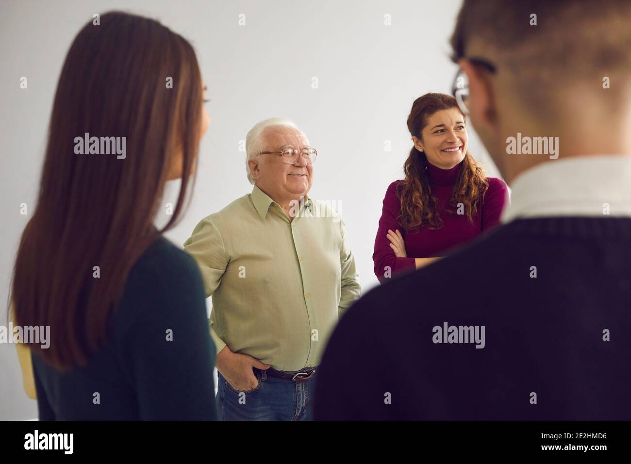 Happy people of different ages talking in group therapy session or community club meeting Stock Photo