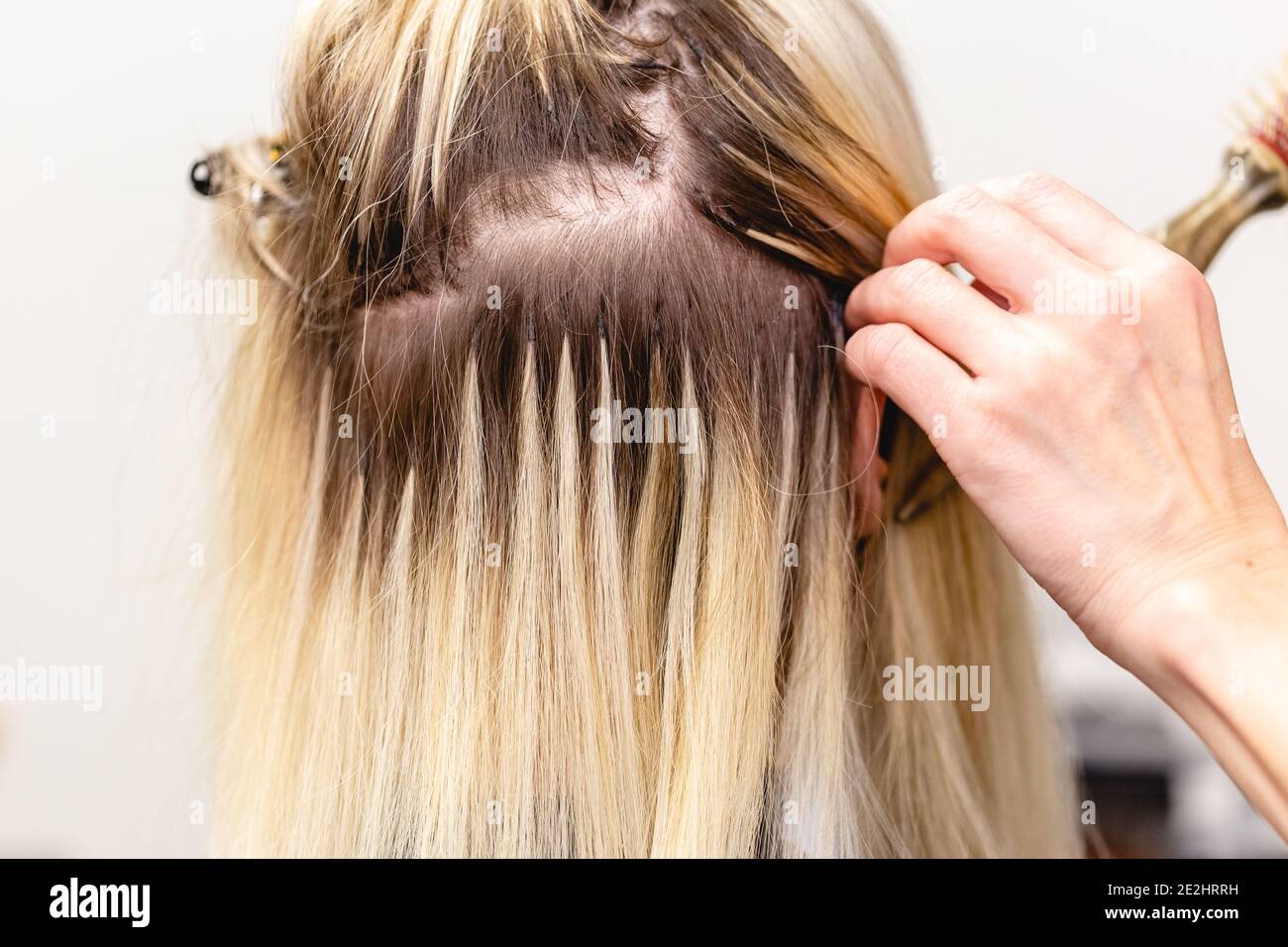 Hair extensions correction procedure. Hairdresser does hair extensions