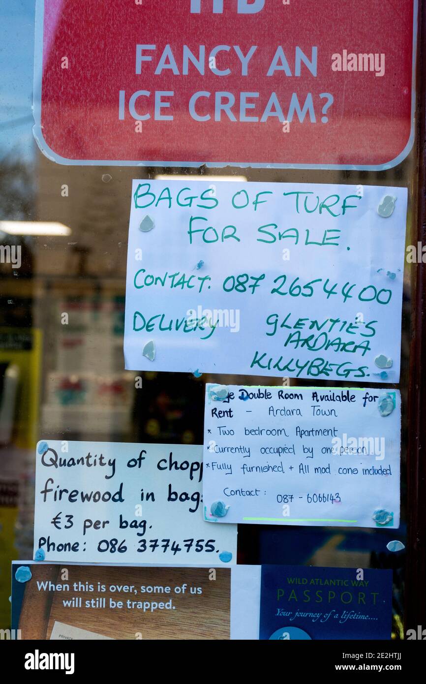 Turf and logs for sale advertisements in a shop window, County Donegal, Ireland Stock Photo
