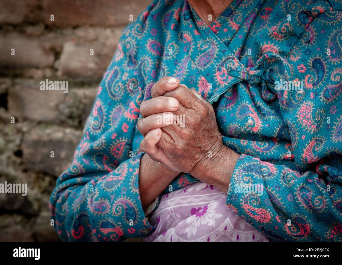 Unrecognized elder woman wearing blue cloths crossing her wrinkled hands. Aging age process Stock Photo