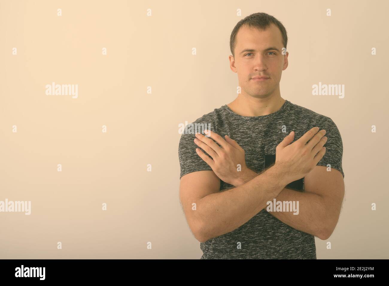 Studio shot of young muscular man with both arms crossed on chest