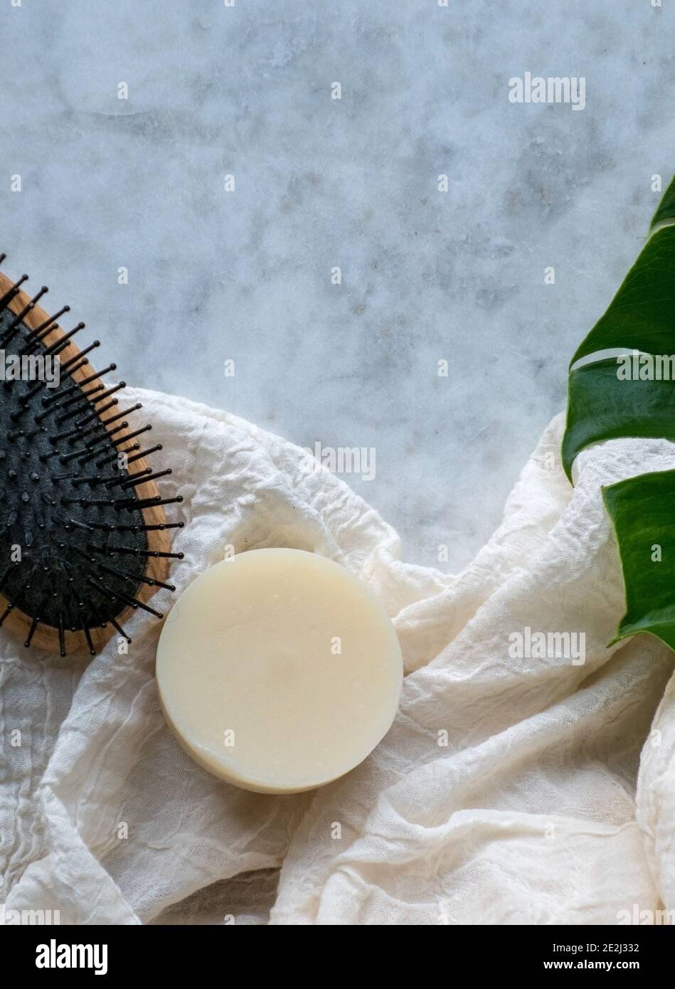 Solid Shampoo bar with Argan Oil isolated on a marble board and a hair brush Stock Photo