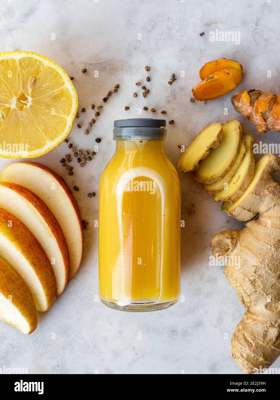 Healthy immune system boosting orange, apple and lemon ginger shot in a small glas bottle Stock Photo