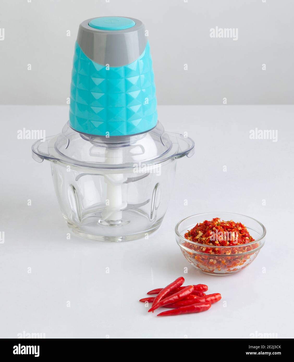 Food processor with chilli and chopped chilli in a bowl isolated on