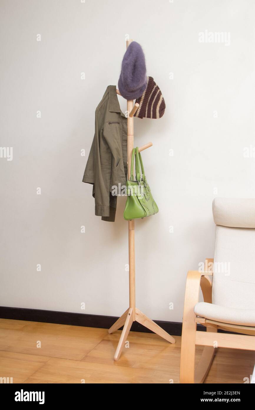 Wooden coat rac k with jacket, hats and handbag in the room background Stock Photo