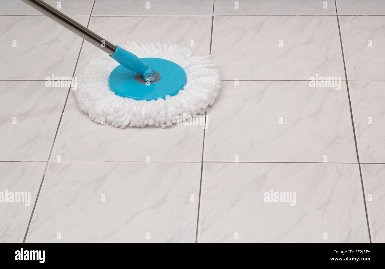 Blue cleaning mop on white ceramic tile floor background Stock Photo