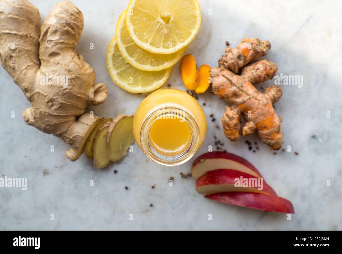 Healthy immune system boosting orange, apple and lemon ginger shot in a small glas bottle Stock Photo
