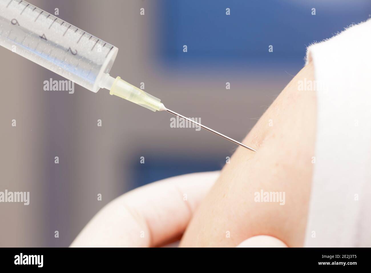 Close-up of vaccination against covid-19 with syringe in upper arm - focus on the needle Stock Photo