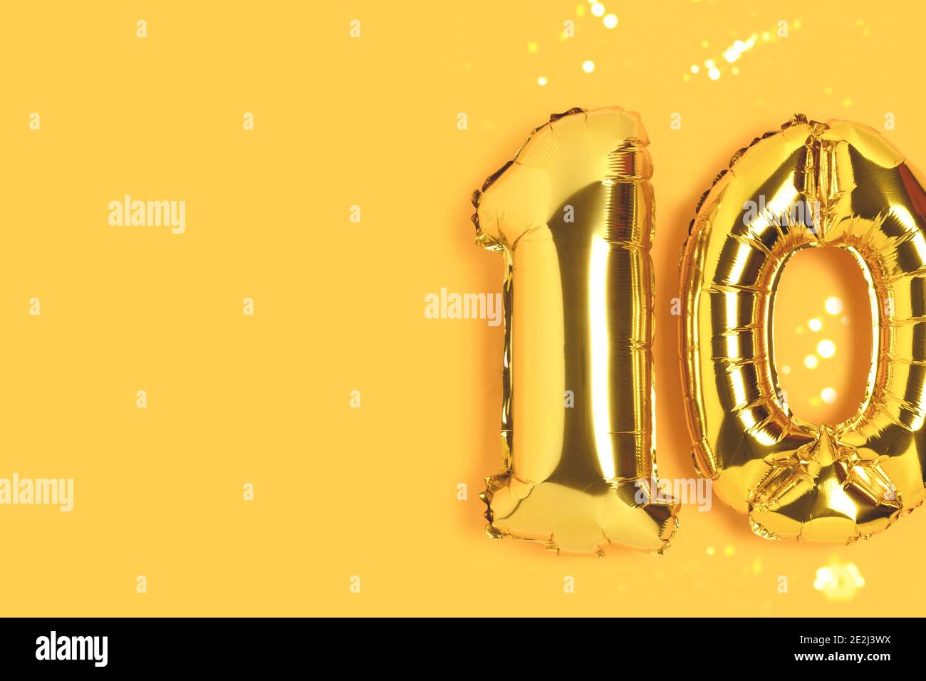 Number 10 golden balloons with gold bokeh. Ten years anniversary  celebration concept on a yellow background Stock Photo - Alamy