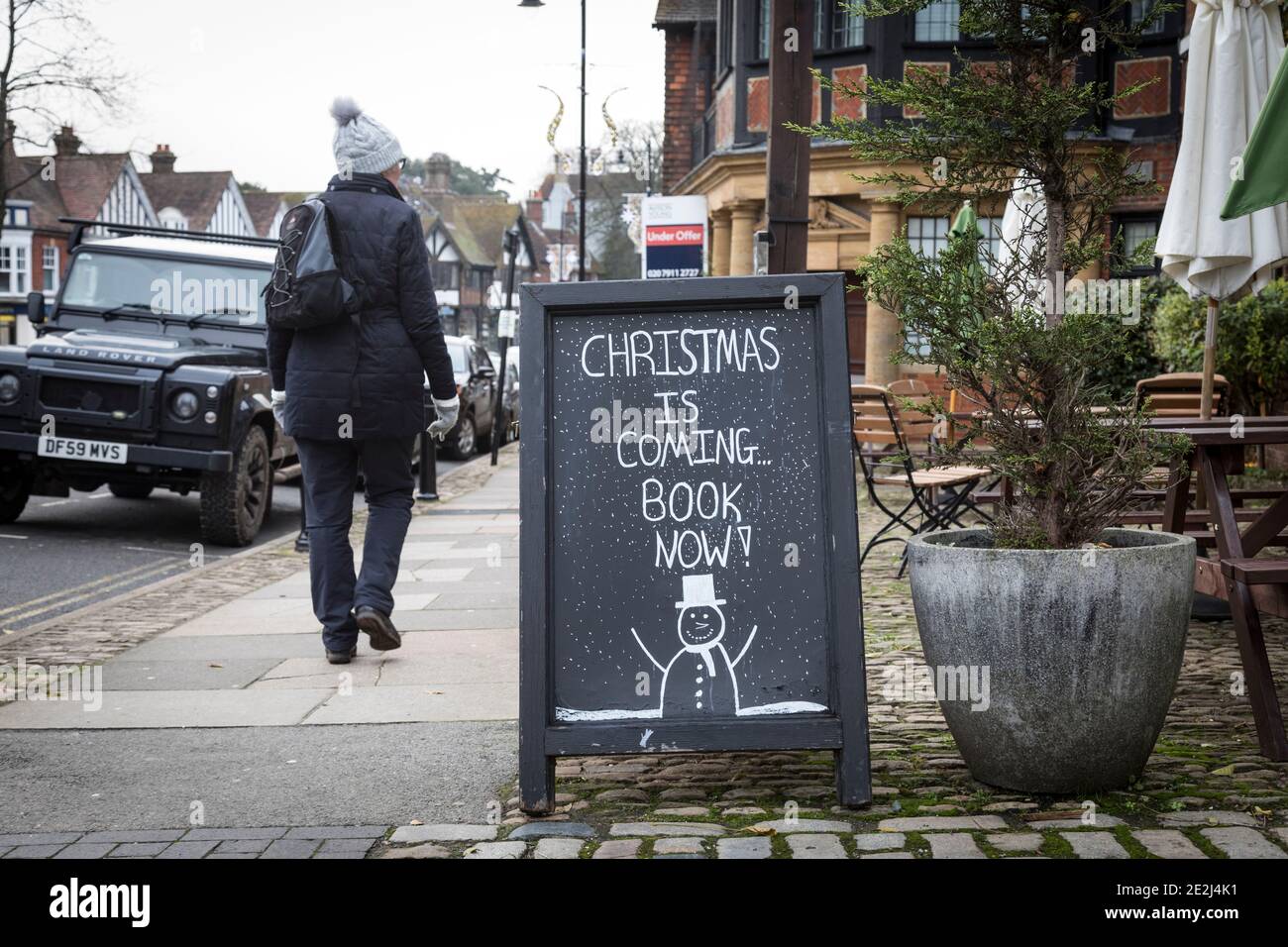 Woman walks past a blackboard offering Pub booking for Christmas, Haslemere, Surrey. Stock Photo