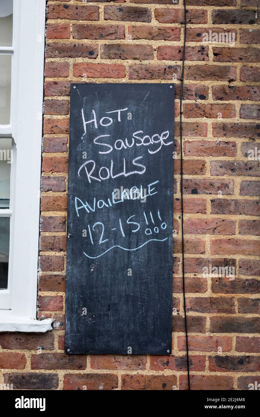Blackboard on a wall outside a shop advertising Hot sausage rolls. Stock Photo
