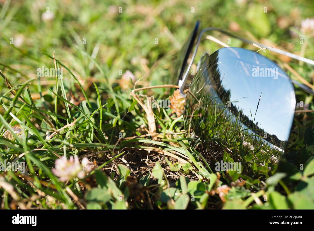 Sunglasses on the green grass. The glasses reflect a clear summer day with a beautiful landscape. Outdoor recreation concept Stock Photo