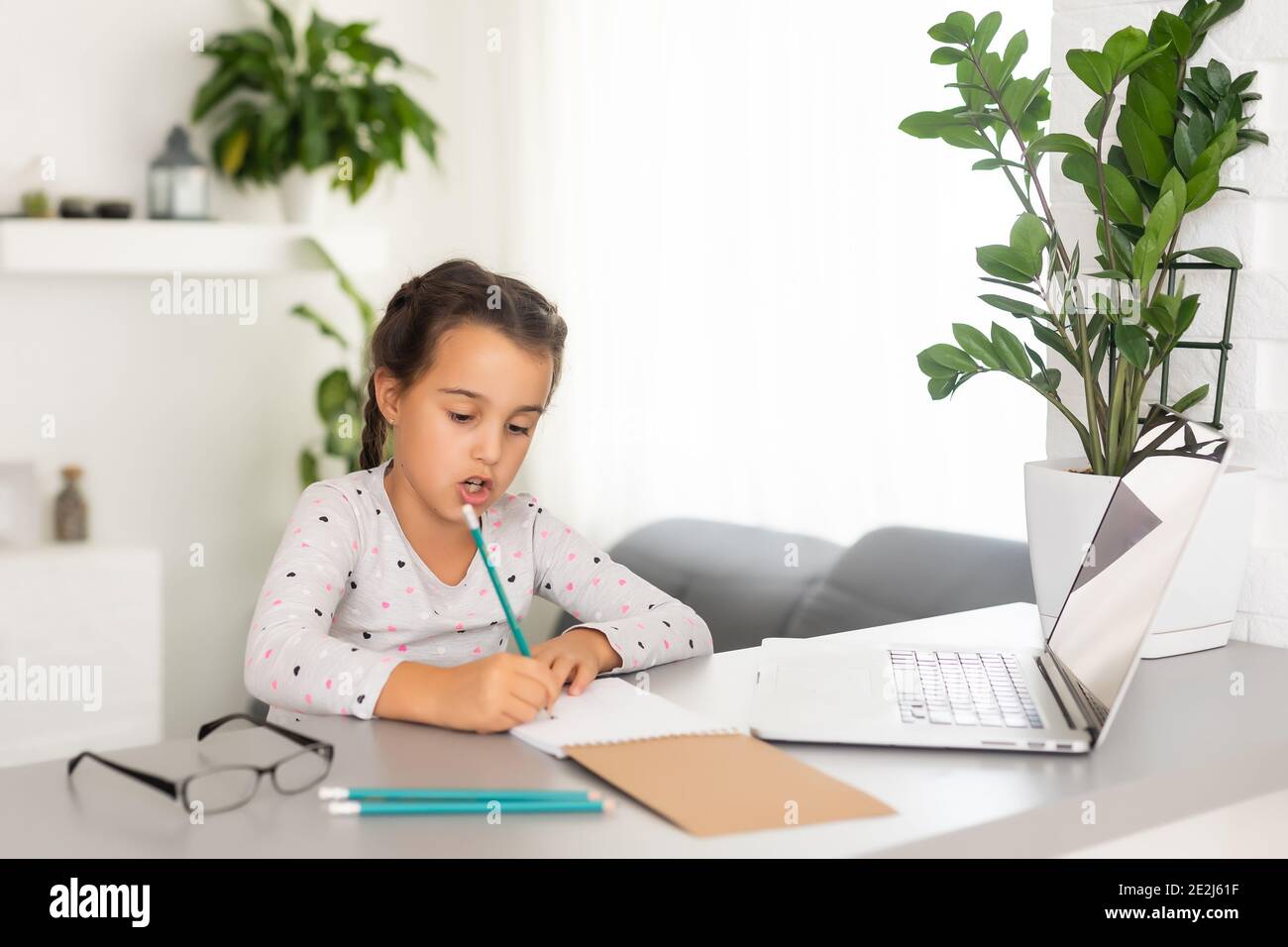 Little girl studying online using her laptop at home Stock Photo - Alamy