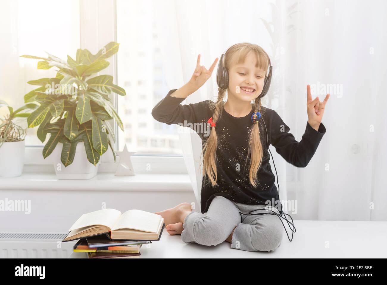 Adorable little girl with headphones sitting on the table at home Stock ...