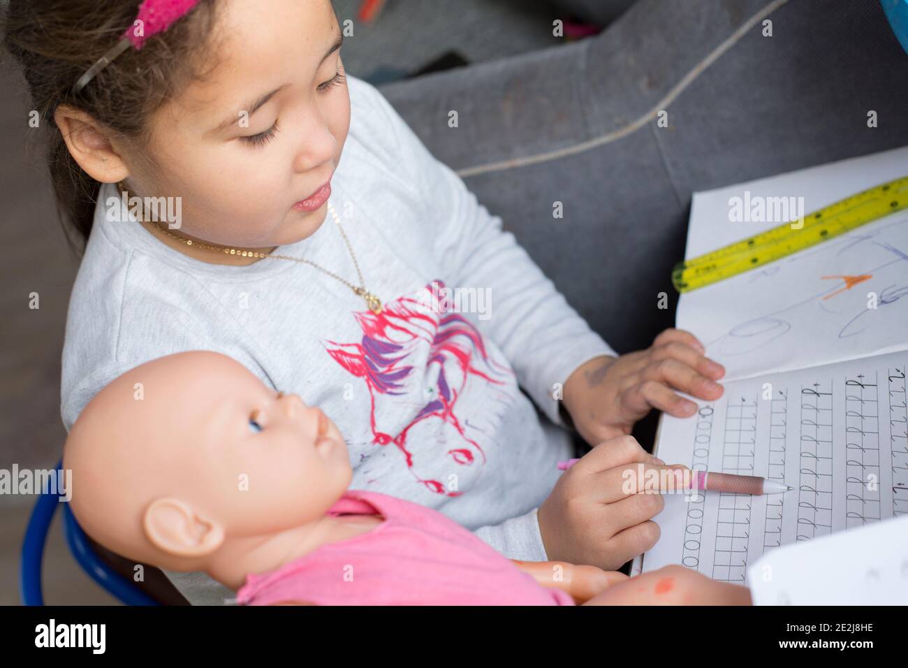Pretty little kazakh girl teaching dool at home school. Home education Stock Photo