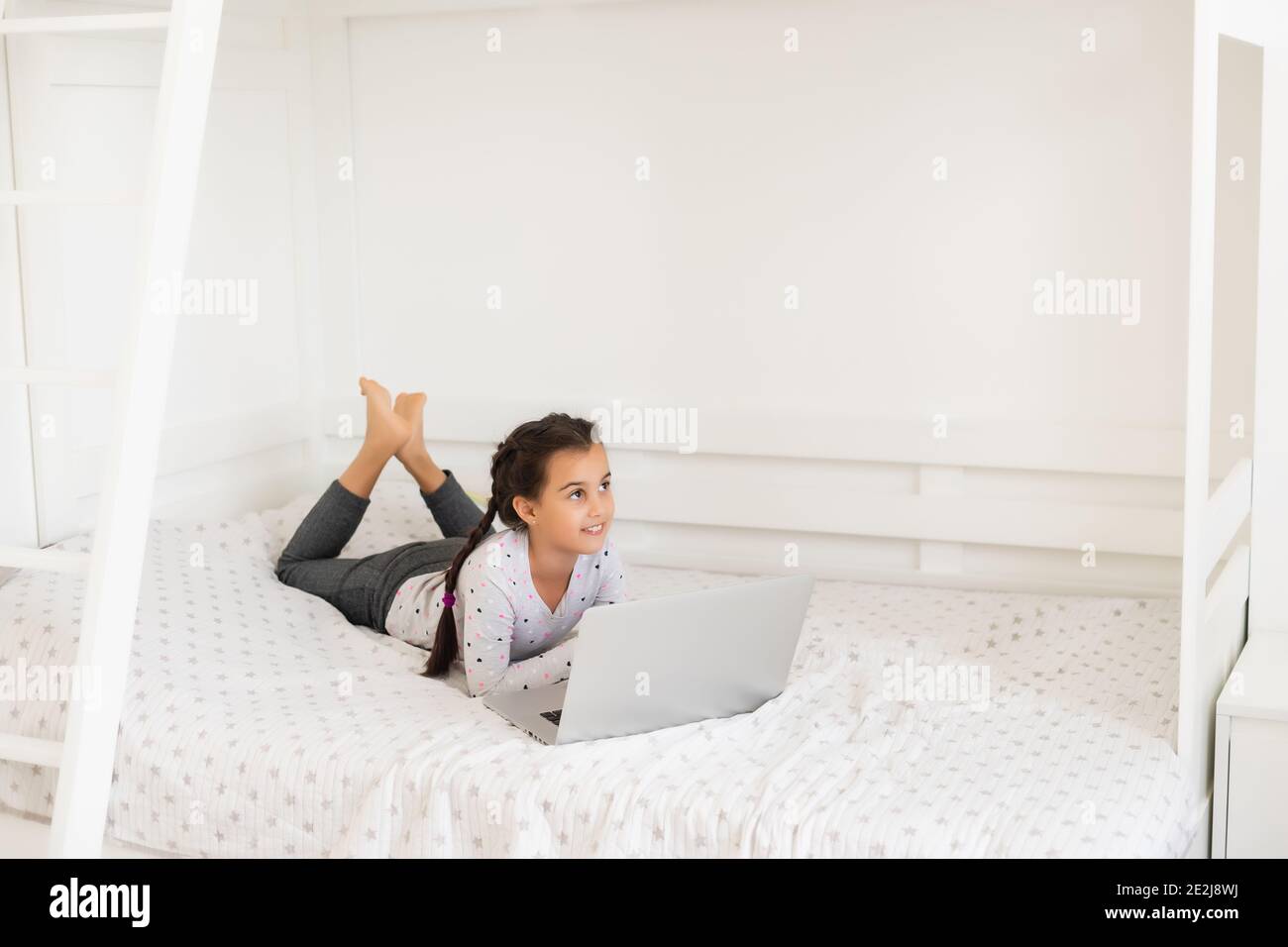Little girl studying online using her laptop at home Stock Photo - Alamy