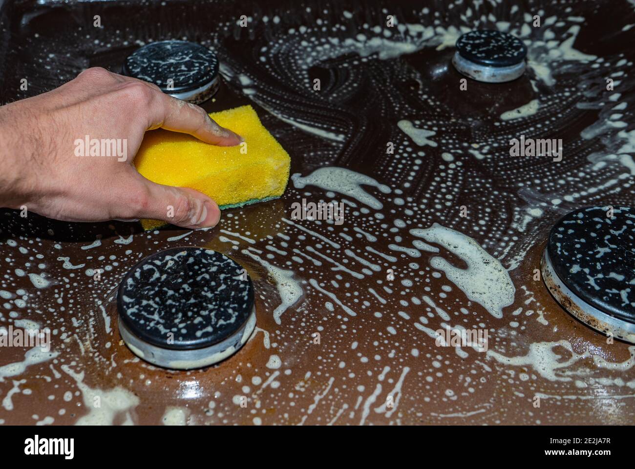 Cleaning and washing of the cooking surface of the stove. Removing fat from the gas stove Stock