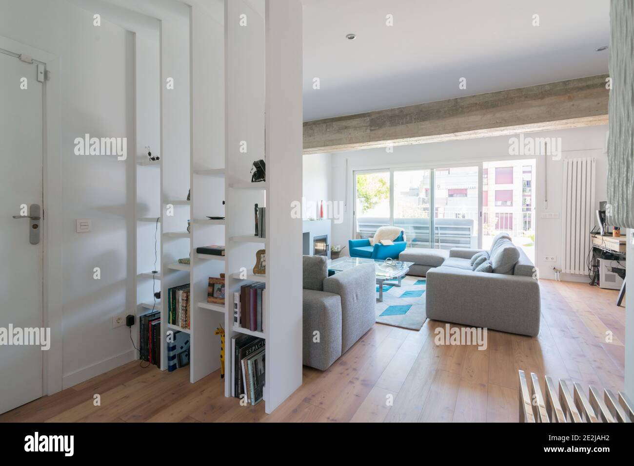 Modern living room with chimney, grey sofas, a green chair and a glass