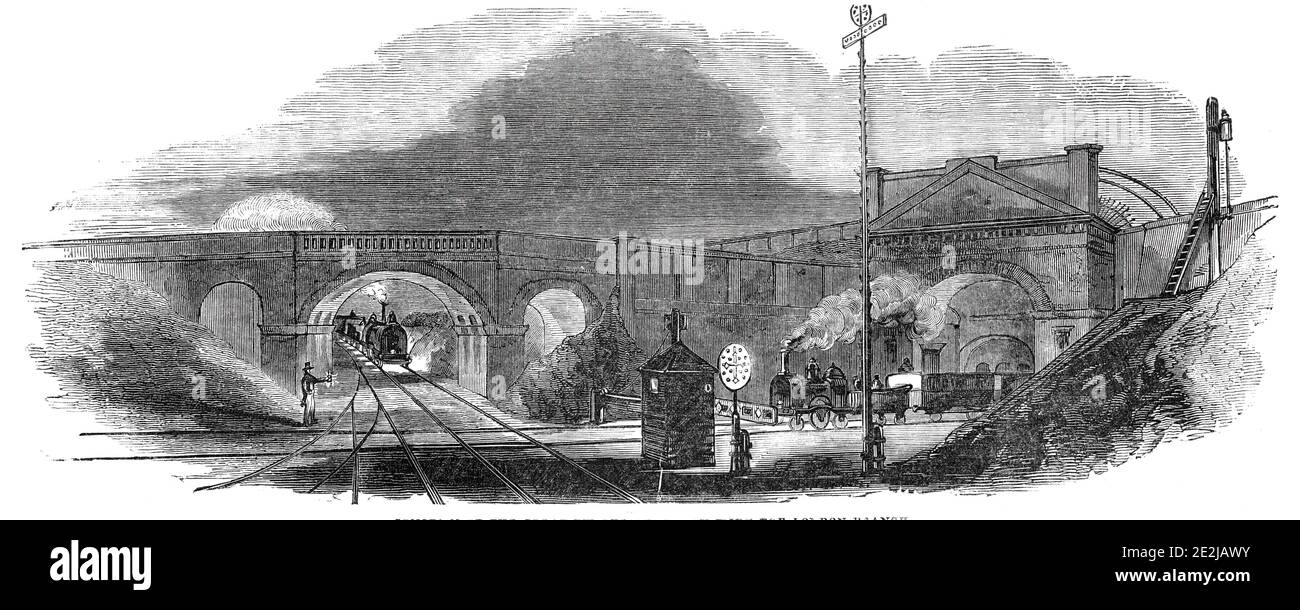 Junction of the Great Western Railway with the London Branch, 1844. 'Two signal-posts of great size, and conspicuous for their markings and colour, have been placed on the left of the up line, in the angle formed by the junction of the two lines. One of these posts - a very tall one - is devoted to the use of the Great Western Line; and the other - a short one - to the use of the West London'. The signals '...are so arranged that the one is made to work relatively with the other. Thus, when the full face of the cross bar of the branch post is turned full on the line, giving warning &quot;To St Stock Photo