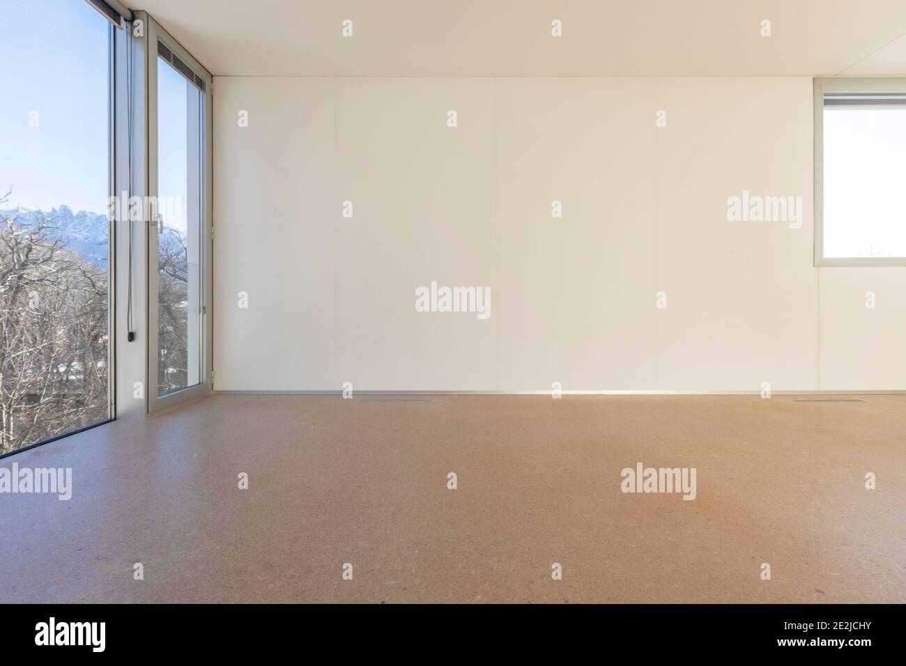 empty sunny room interior with white painted wall, big window and modern wooden floor parquet, new apartment under construction Stock Photo